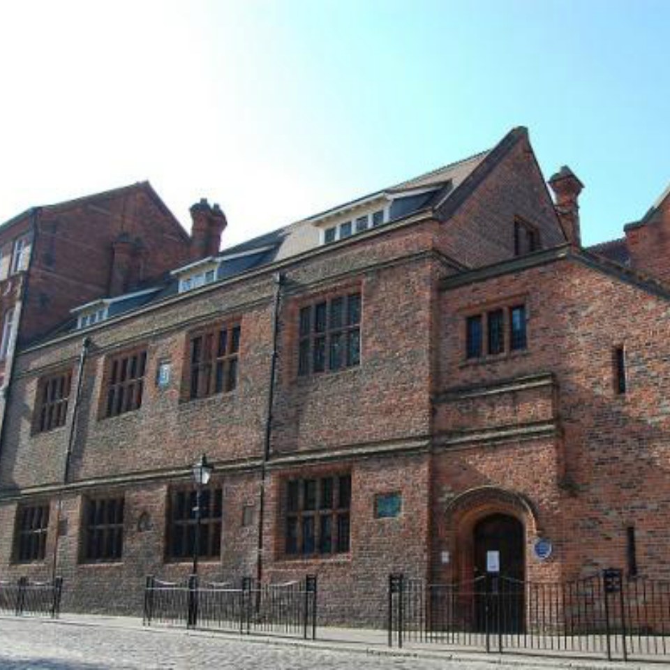 Red Brick building, behind black iron railings and cobbled street 