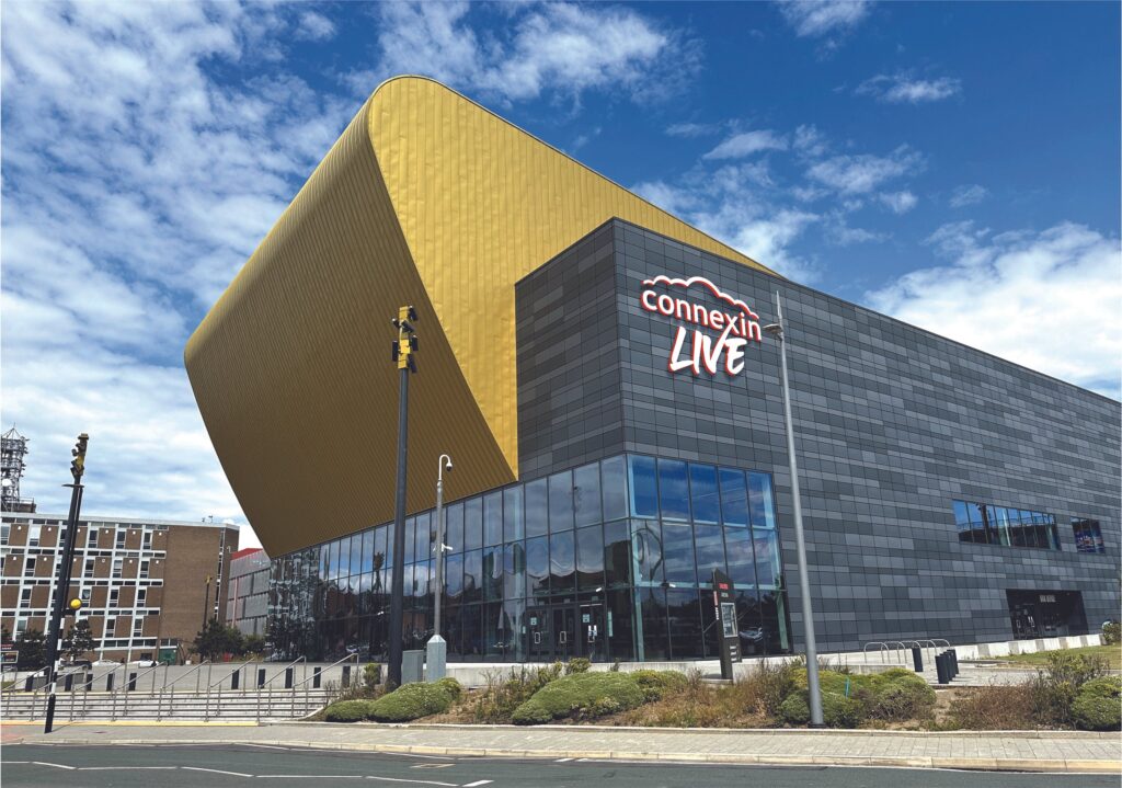 Alt text: "Exterior view of Connexin Arena in Hull, a modern multi-purpose venue with a curved facade and large signage. The arena hosts concerts, sporting events, and entertainment, serving as a key destination in the city