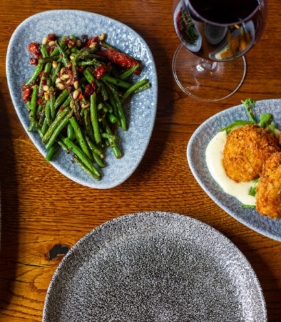 Various Tapas Dishes include Green Bean Salad and Patatas Bravas and glass of red wine