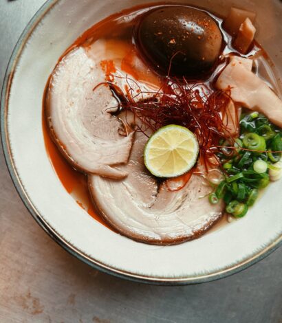 Plate of food including Chicken/Pork Paitan broth. Shoyu ('Soy') Tare. Slow cooked and charred Pork Chashu. Spring onions. Bamboo shoots. Ramen egg marinated in Soy/Mirin/Kombu. Naruto.