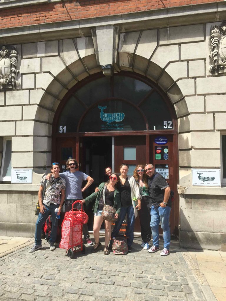 Small group of people with luggage in front of black brick arched doorway