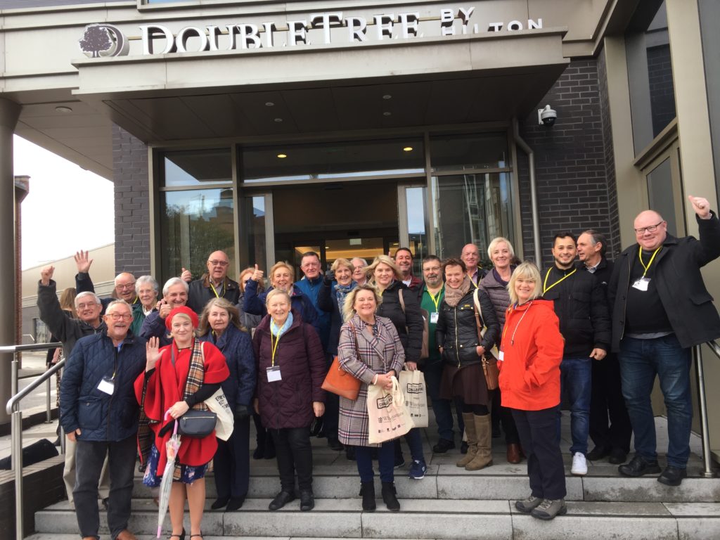 Large group of smiling people on the steps in front of the Doubletree by Hilton Hotel