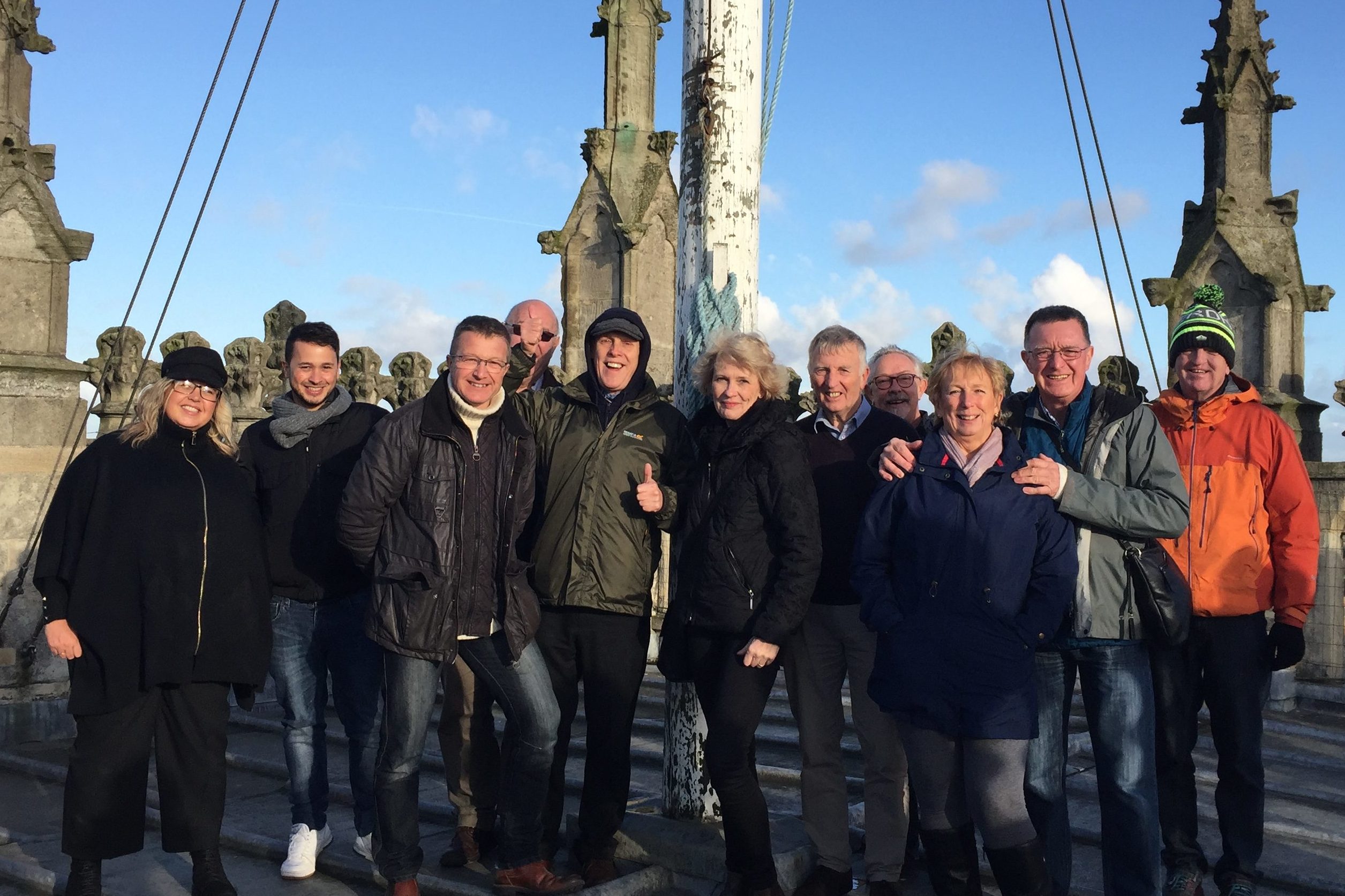 Group of people standing on the roof of Hull Minster in winter attire. They are all smiling.