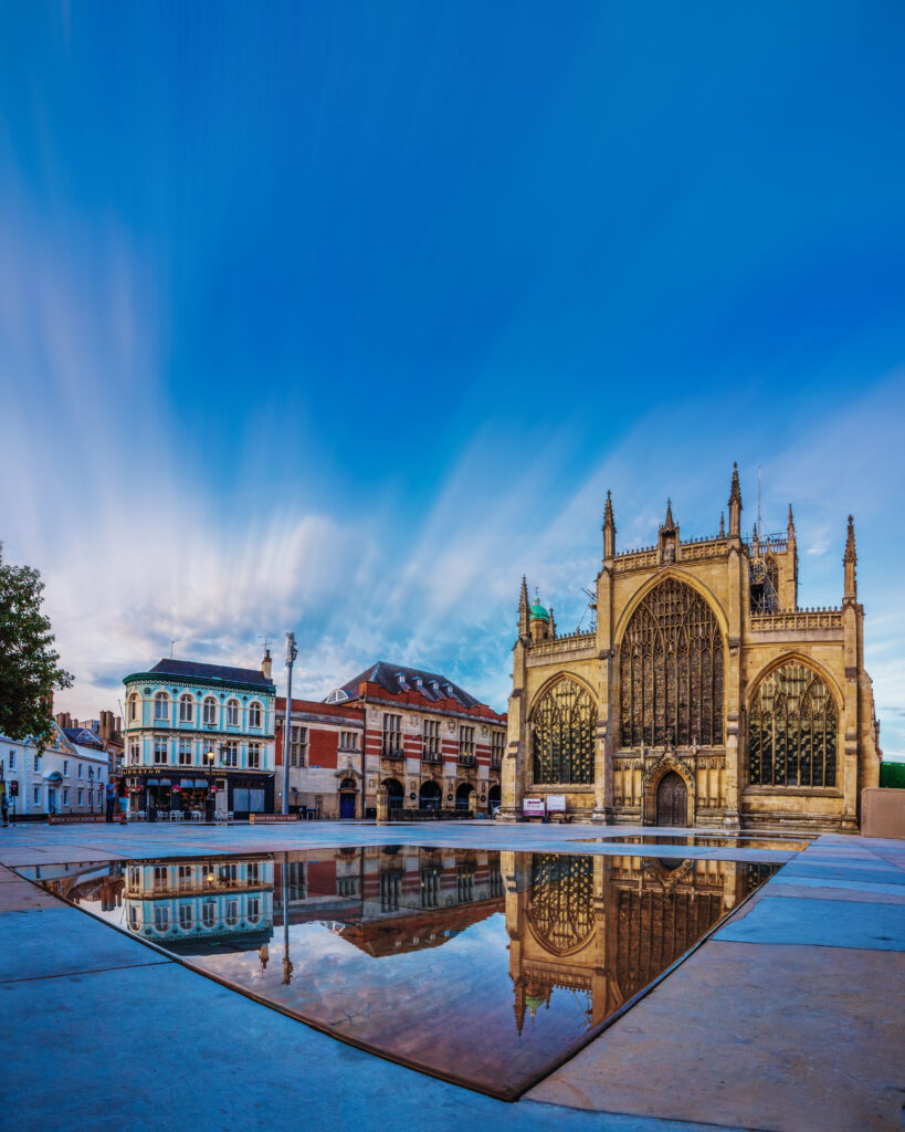 Hull Minster, Larger gothic style church with mirror pools in the foreground, reflecting the building and clear blue sky