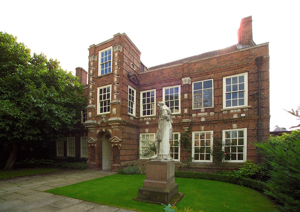 Wilberforce House in Hull, a historic red-brick Georgian building, with the statue of William Wilberforce in the foreground. The statue honors the famous abolitionist, whose former home now serves as a museum dedicated to his life and legacy