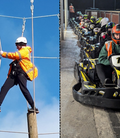 person in Yellow jacket and hard hat walking on stepping logs highropes and line of people in go-karts awaiting start of race