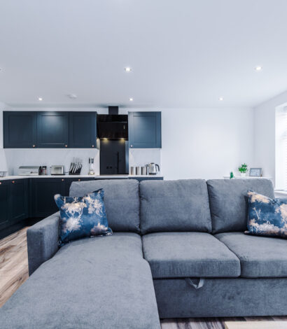 Open plan living space with kitchen and large grey corner sofa