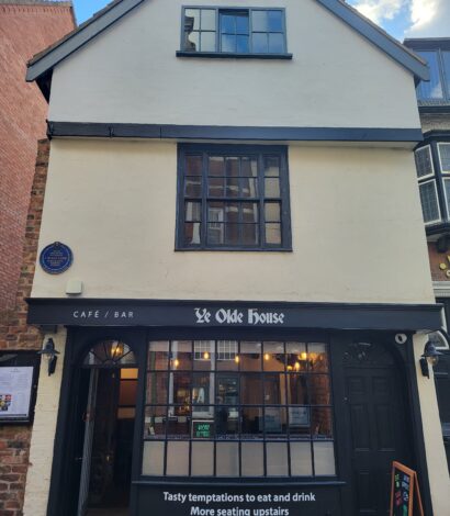 3 story Medieval Middle age Building with black wood frame and Large Georgian style front window. Blue Plaque also visible on the front of the building