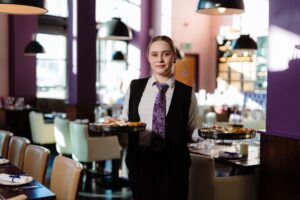 Waitress holding a tray, standing in a beautifully decorated indian restaurant called Tapasya.