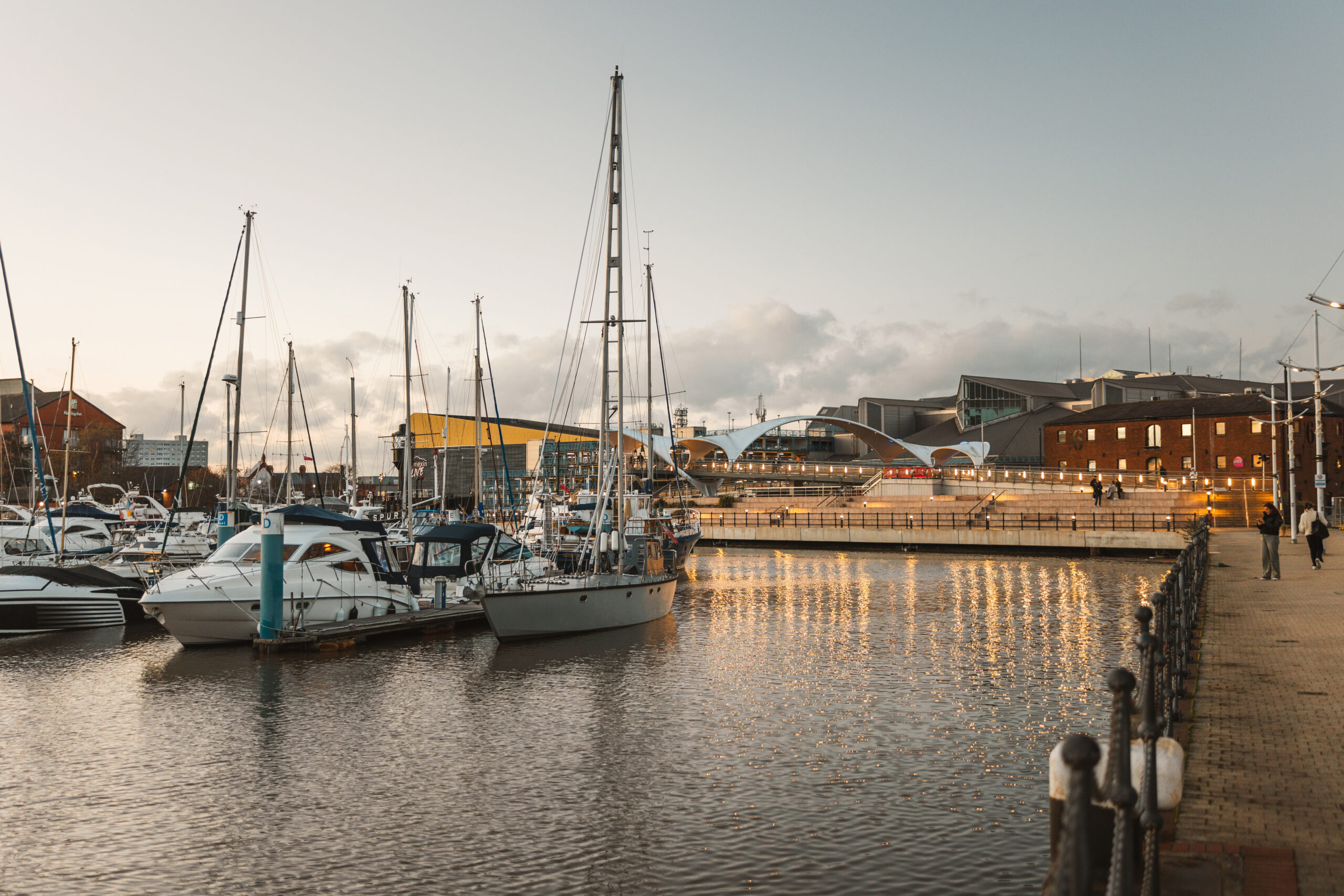 Hull Marina in winter at sunset. The boats and water are in the foreground and the yellow top of Connexin Live is in the background